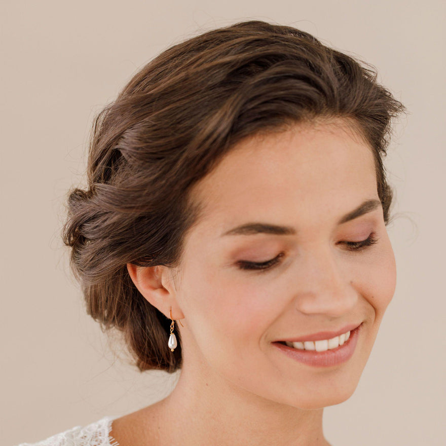 A bride wearing pearl drop earrings