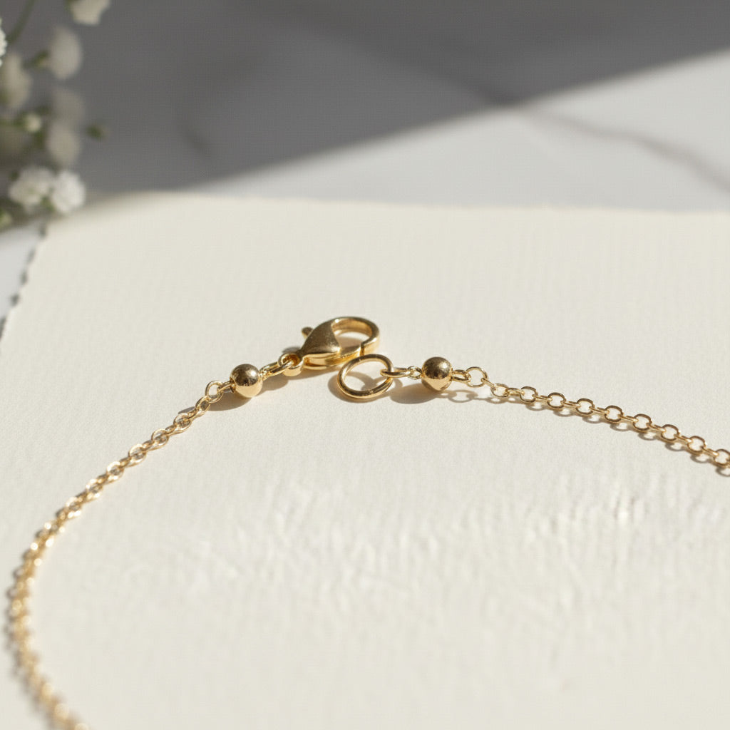 Gold bracelet on a textured white surface with a soft background