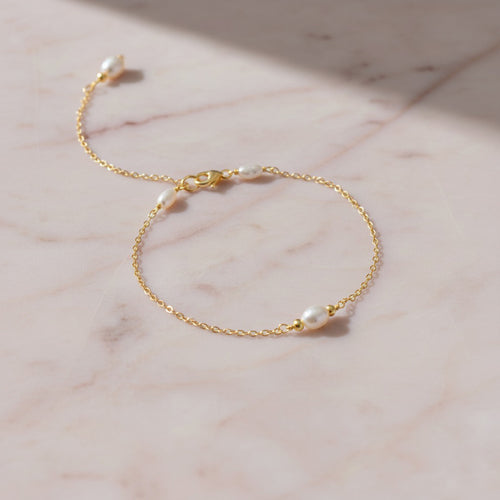 Dainty gold bracelet featuring small freshwater pearls.