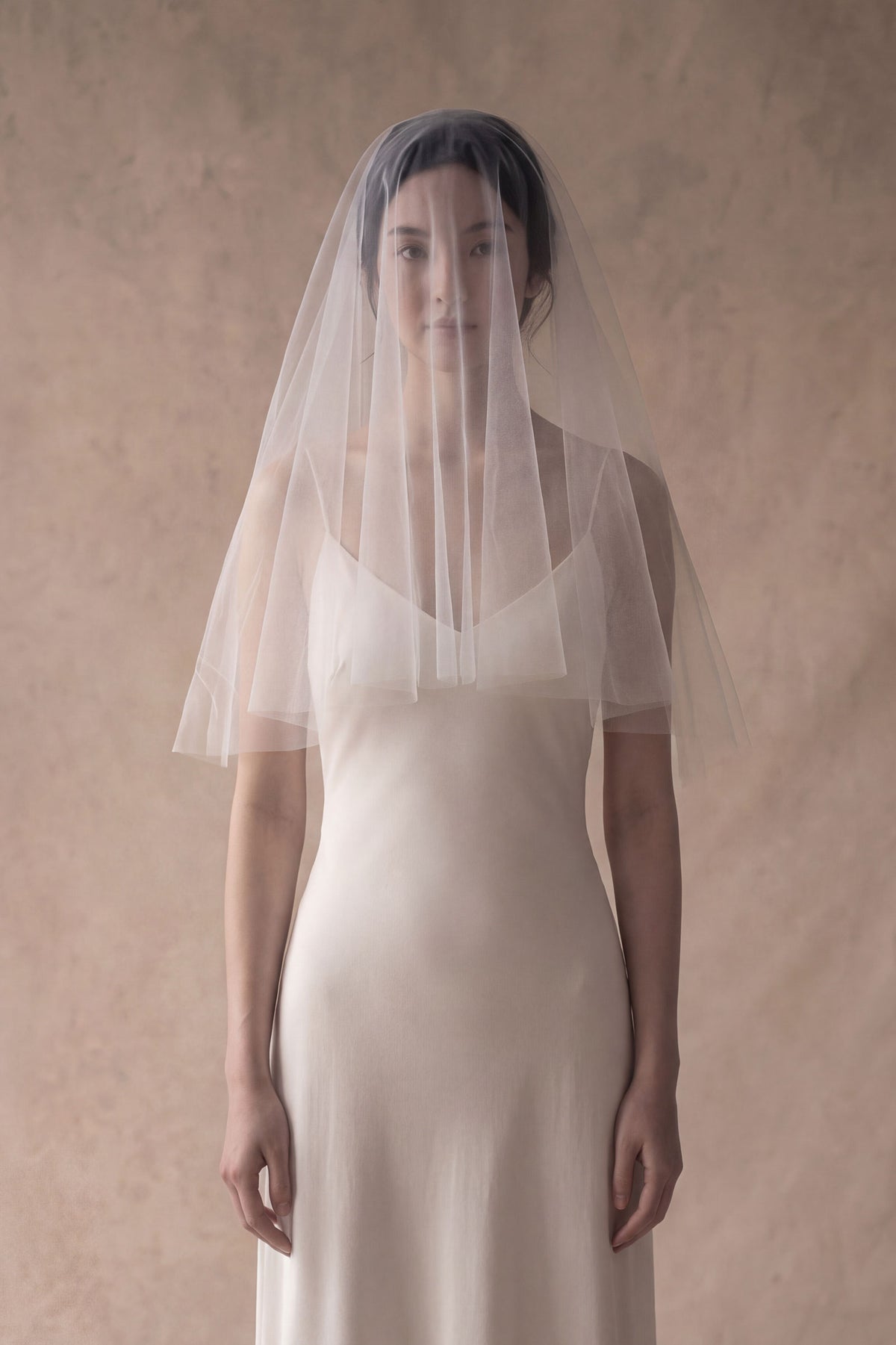 Bride wearing elbow length drop veil with blusher over her face