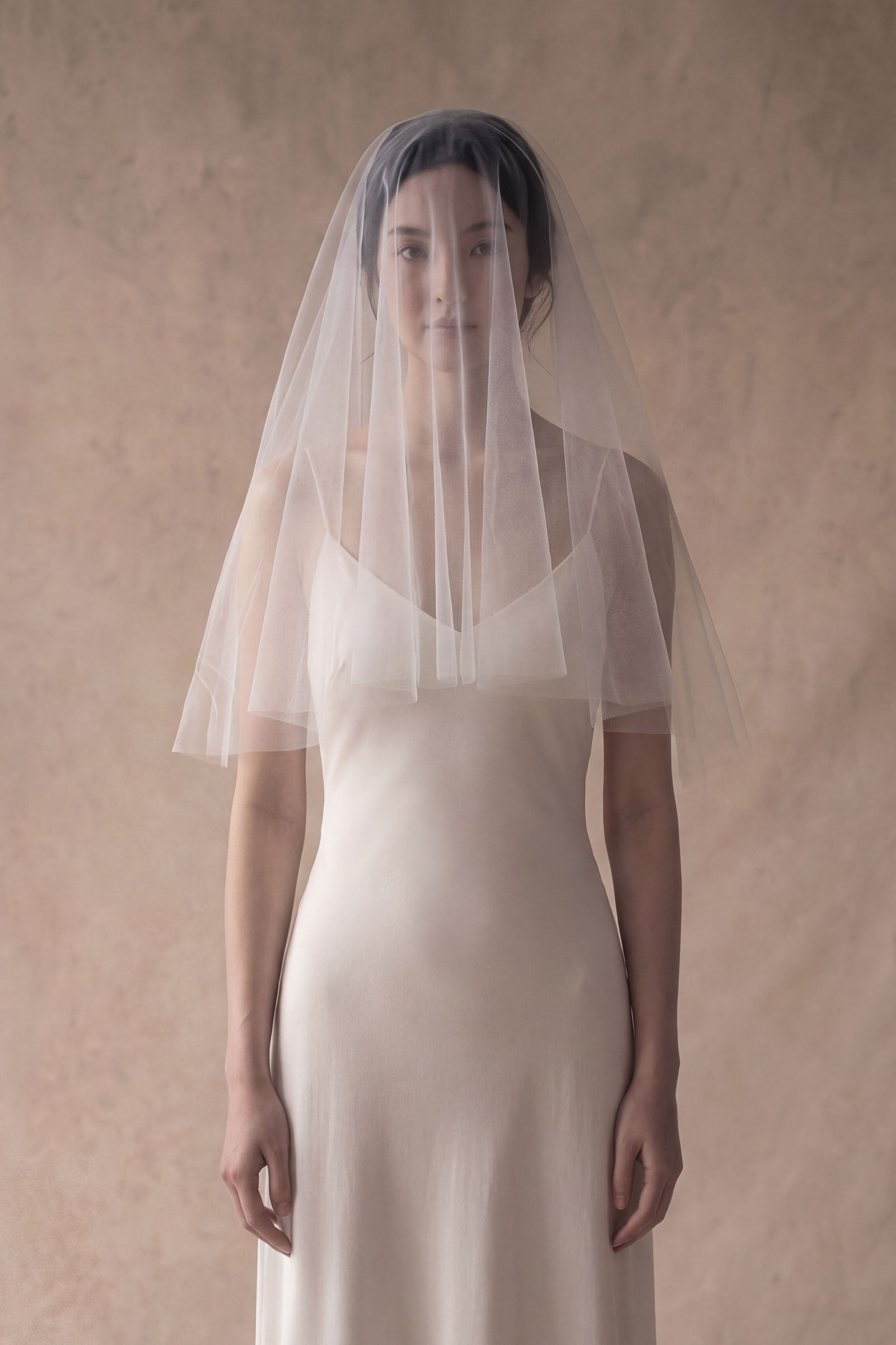 Bride wearing elbow length drop veil with blusher over her face
