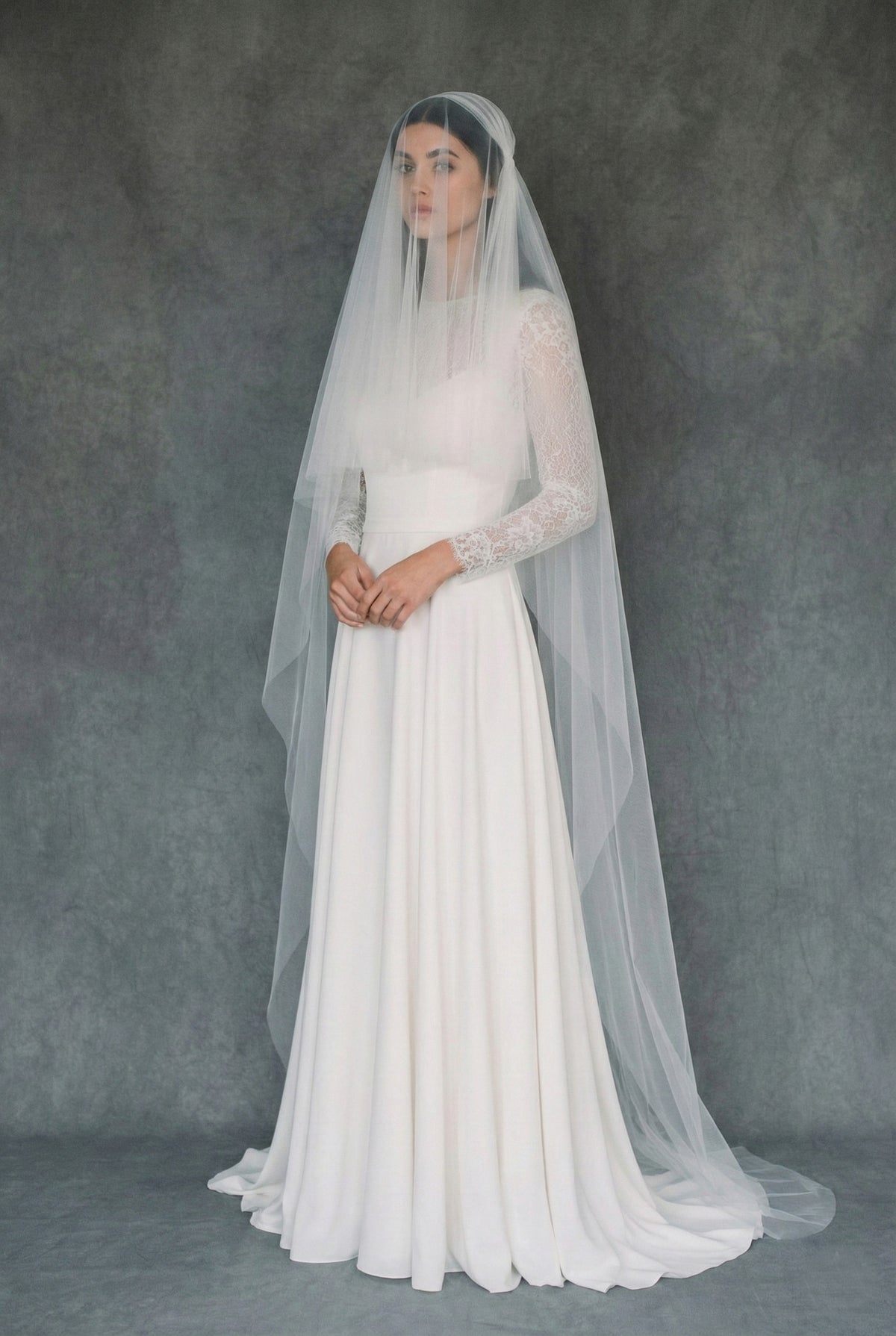 Bride wearing the Zelda two-tier Juliet cap wedding veil made of soft tulle with a simple cut edge finish