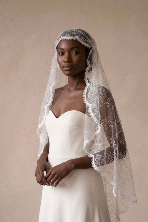 All over lace juliet cap wedding veil in pale ivory, worn fitted to the crown over a strapless dress.
