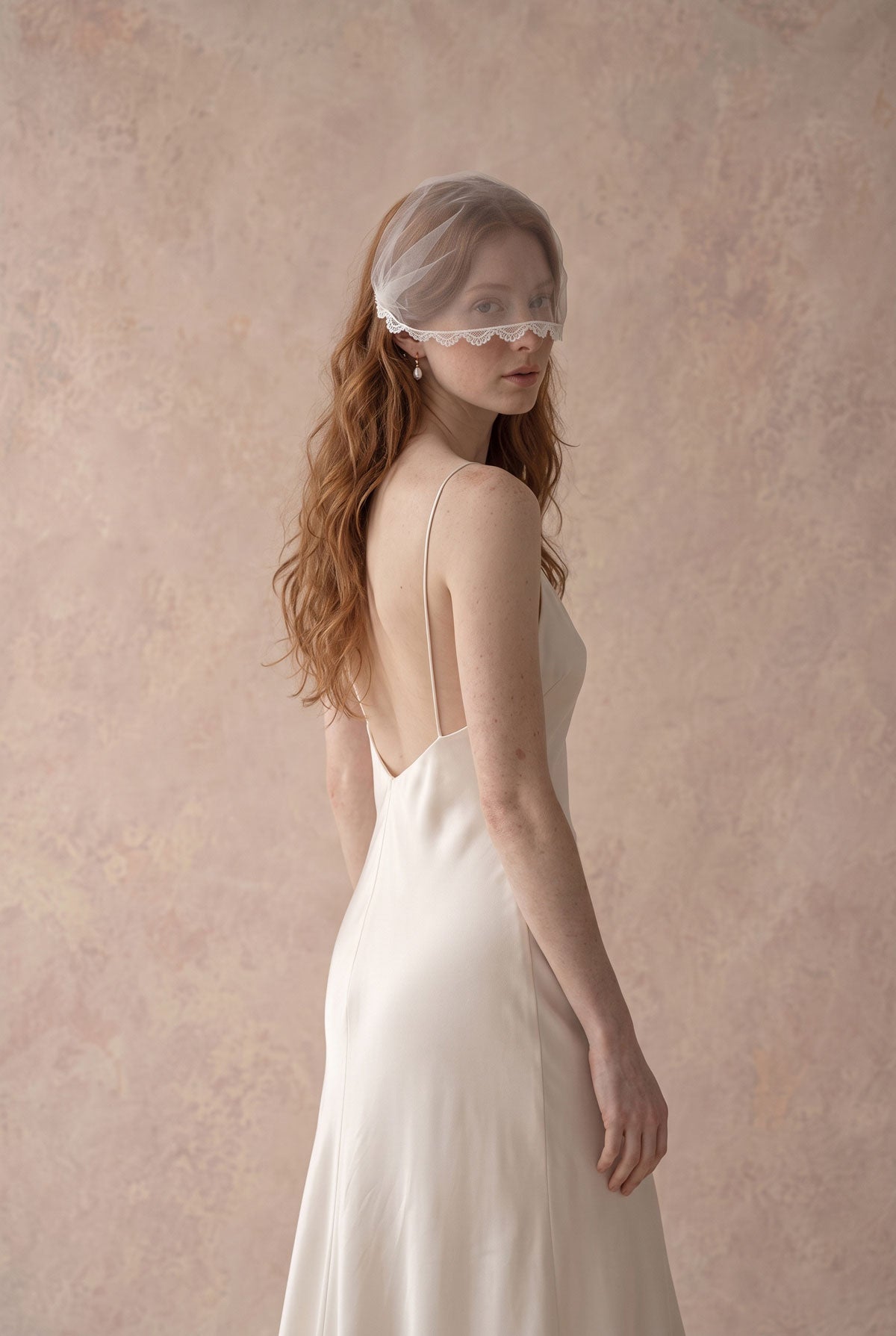 Side view of the Clio lace face veil on combs, worn with long wavy hair