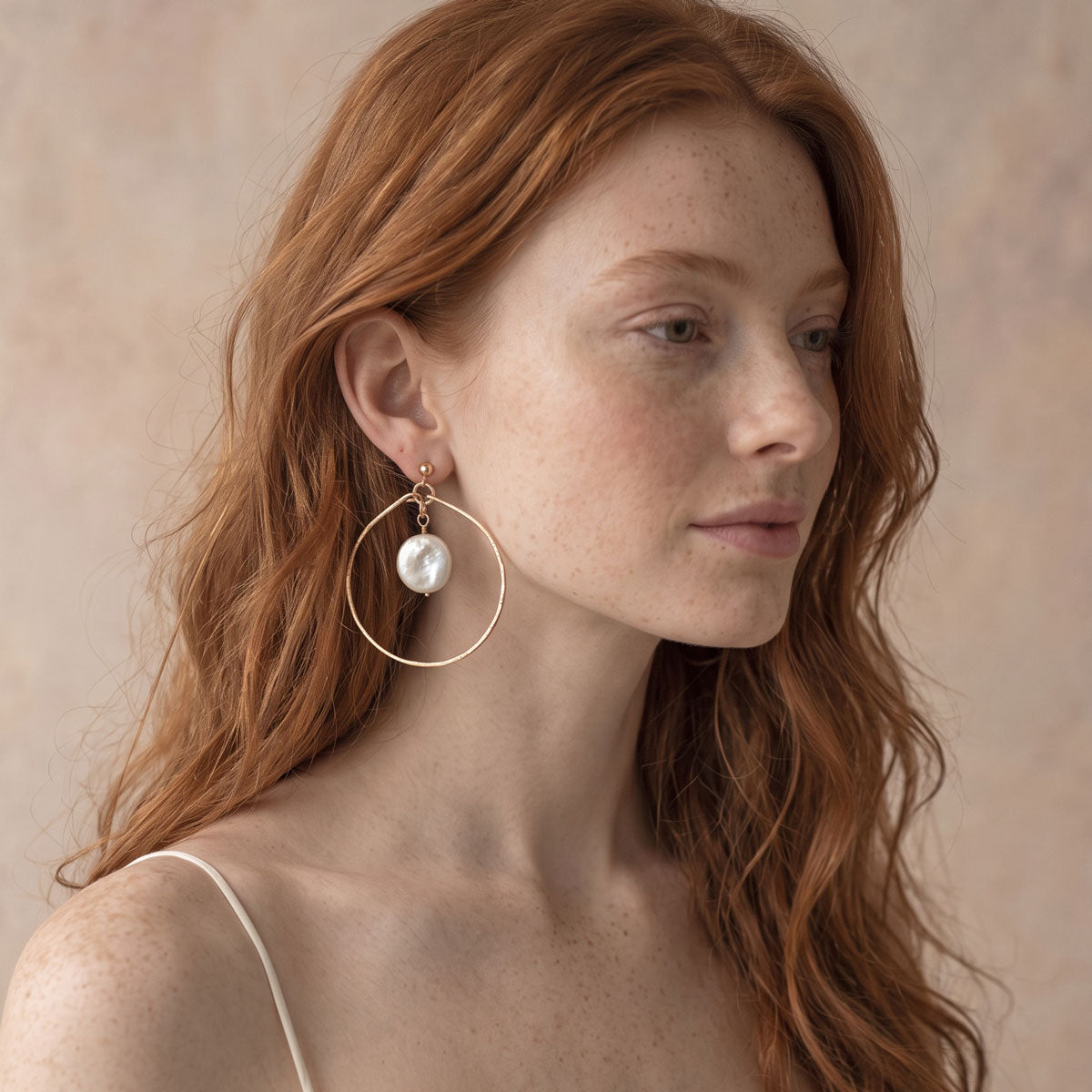 Bride wearing gold filled hammered teardrop hoop earrings with freshwater coin pearl drops.