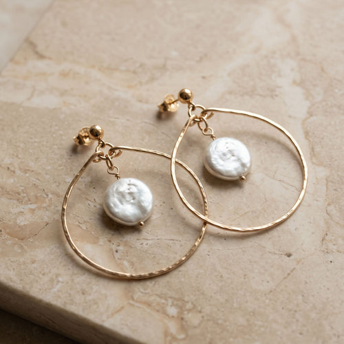 Gold filled hammered teardrop hoop earrings with freshwater coin pearl drops, displayed on cream marble