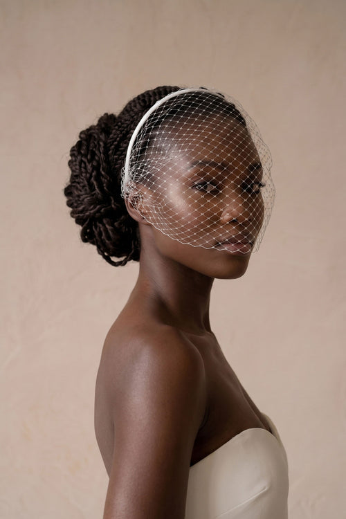 Bride in profile wearing an ivory Russian net birdcage veil on a slim satin headband