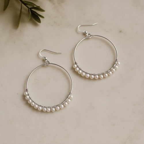 Silver hoop earrings adorned with delicate freshwater pearls, elegant handmade bridal jewellery by Britten Weddings.